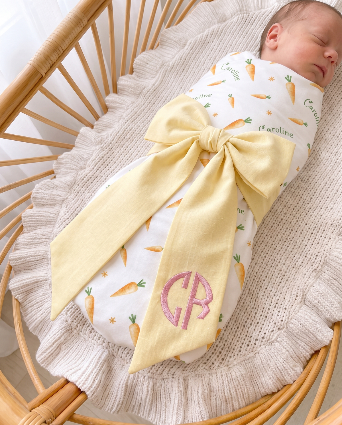 Close-up of the light yellow bow sash with pink embroidered monogram