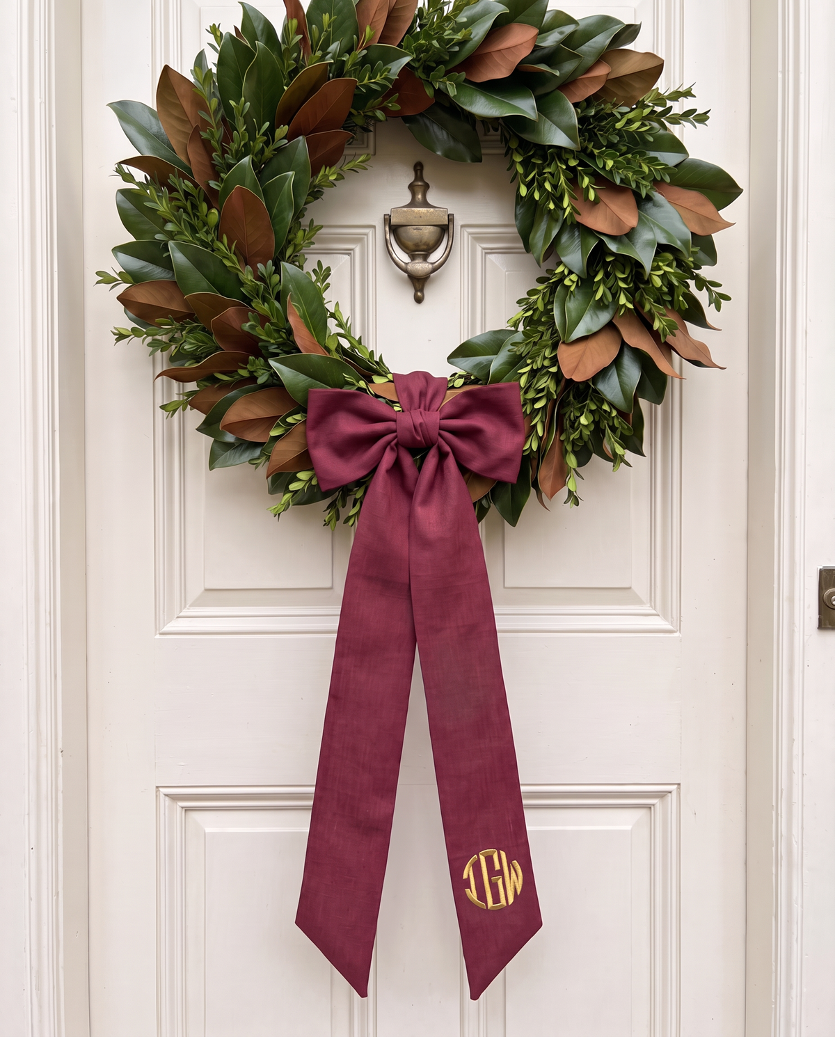 Burgundy bow sash on a cream wooden door wreath