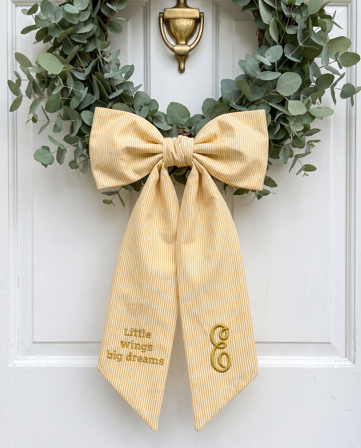 Striped yellow bow sash on a white door with a leaf wreath