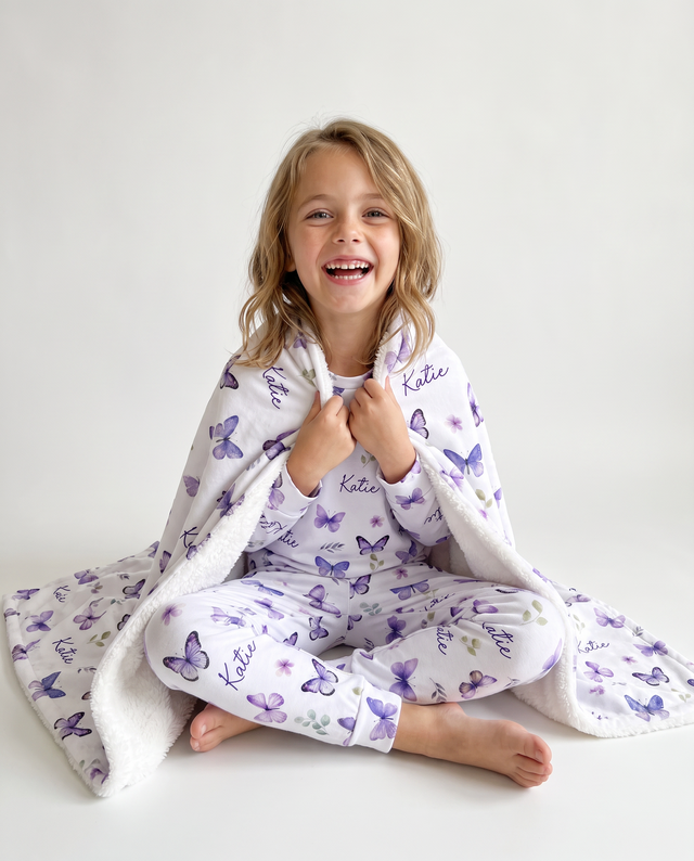 Girl in purple butterfly pajamas wrapped in the matching personalized blanket