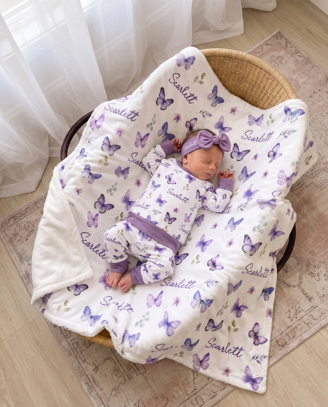 Newborn in a purple butterfly bow headband tucked under the personalized blanket in a basket