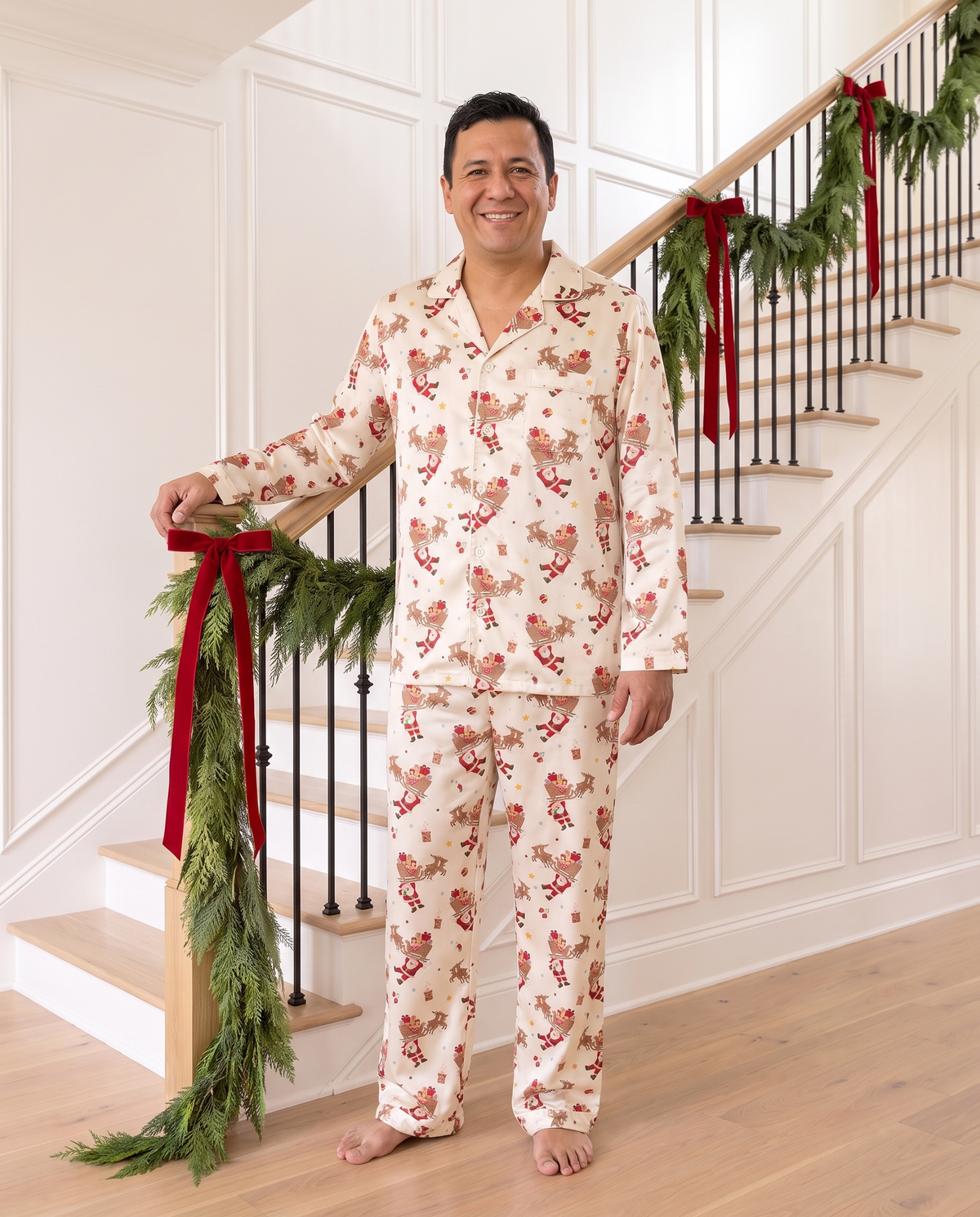 Man in Santa's Joyride pajamas at the foot of a garland-trimmed staircase