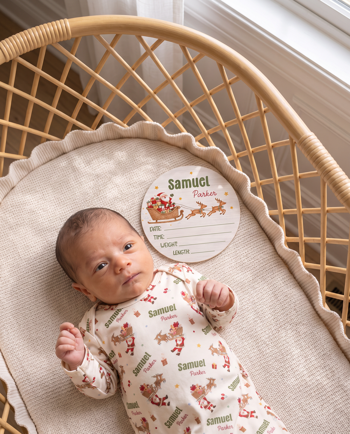 Newborn in a rattan bassinet with the Santa's Joyride birth stats sign by the window