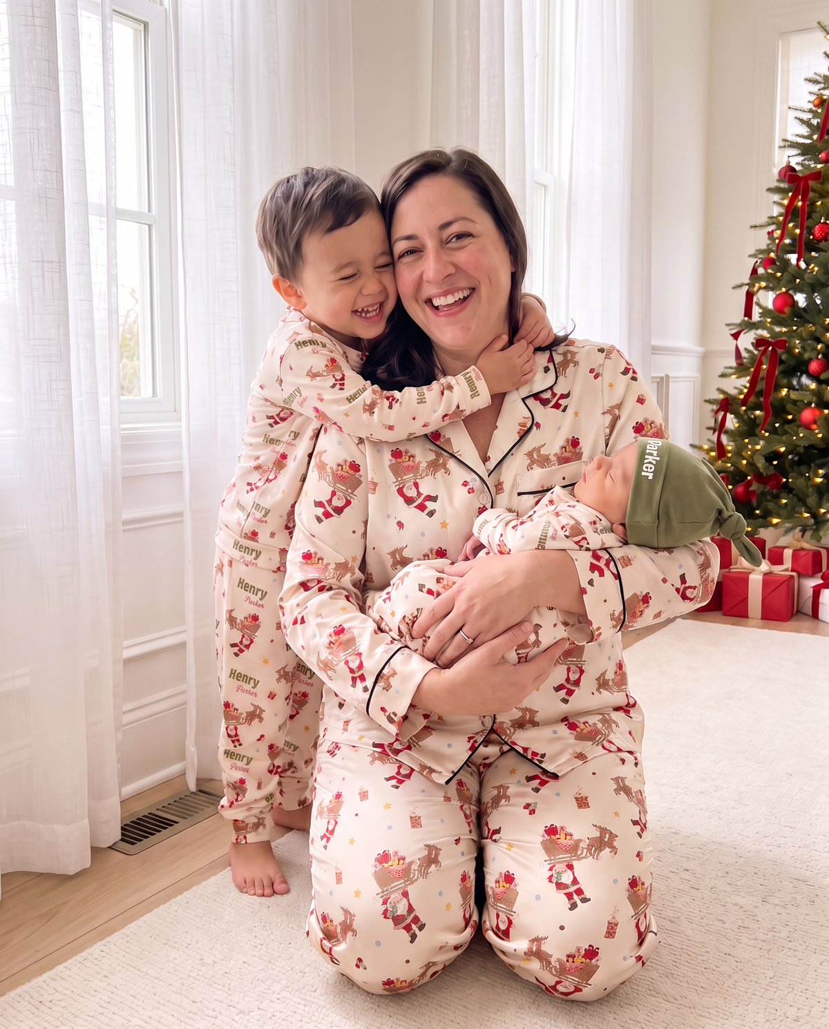 Mom in Santa's Joyride pajamas hugging her kids by the window