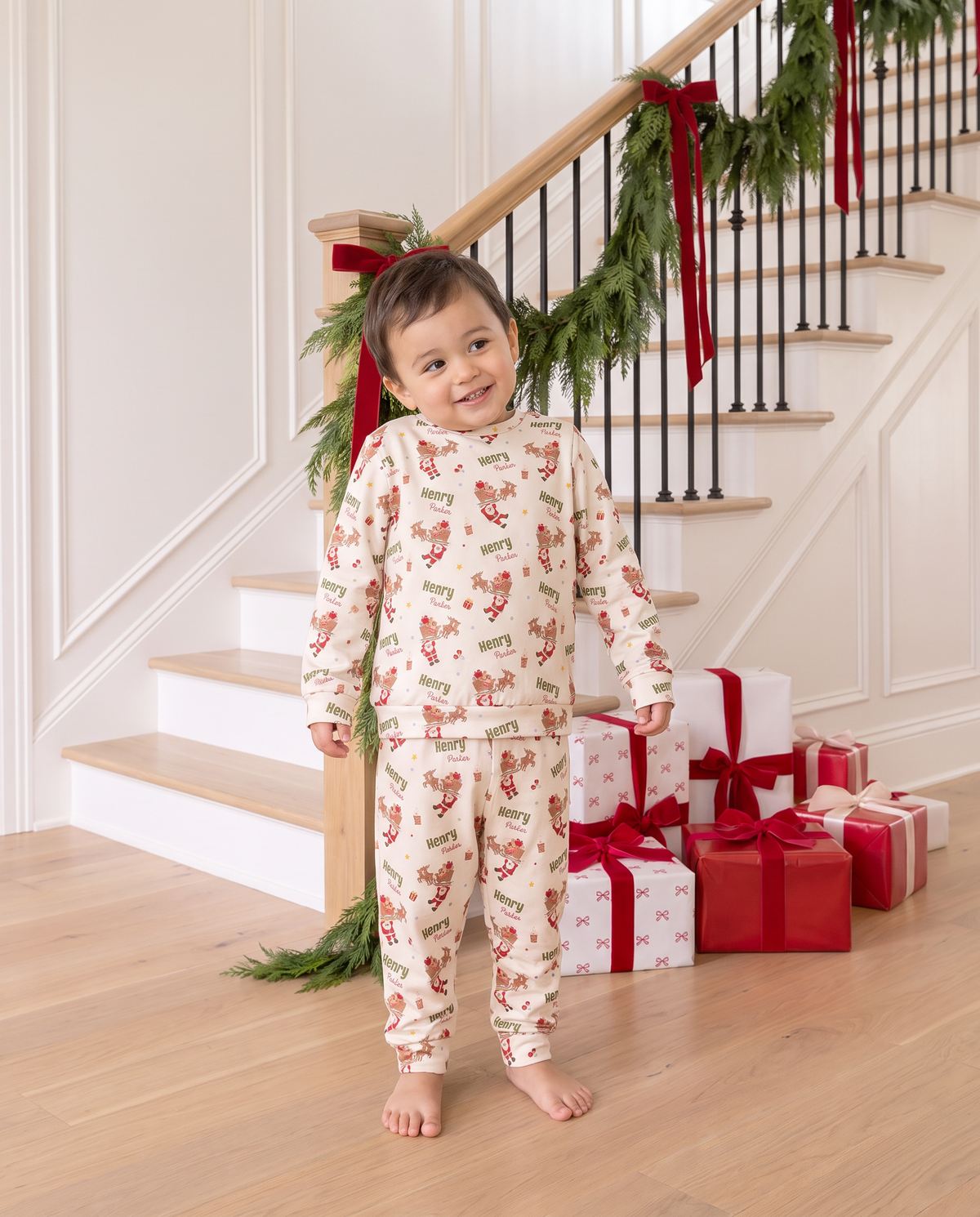 Boy in the personalized Santa's Joyride pajamas by the staircase with gifts