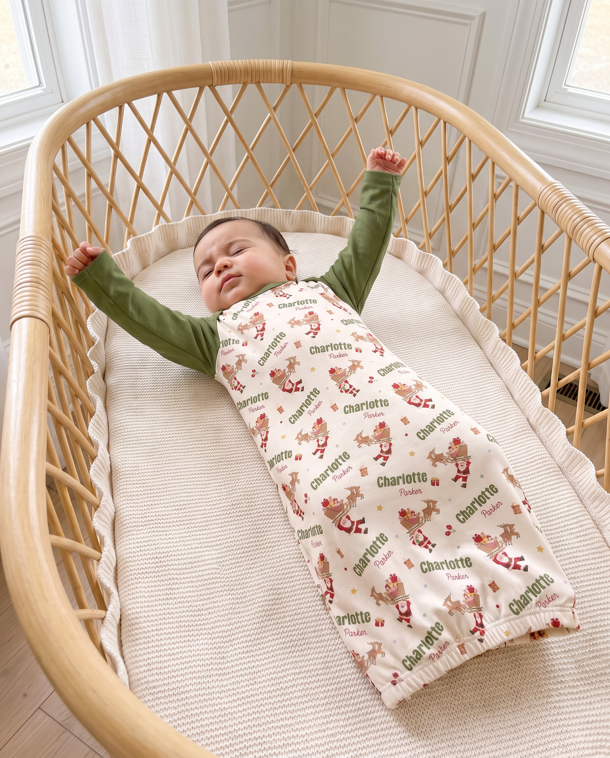 Baby stretching in Santa's Joyride sleep gown inside a rattan bassinet