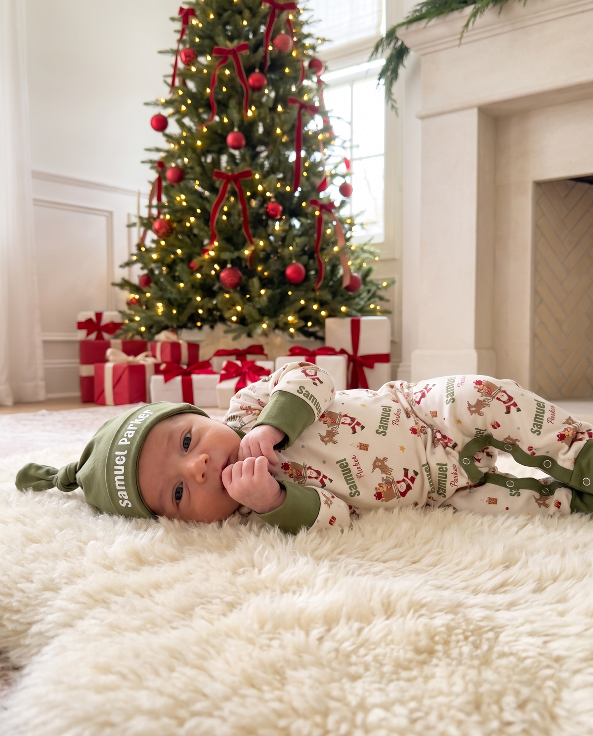 Baby in Santa's Joyride romper resting on a soft rug by the Christmas tree