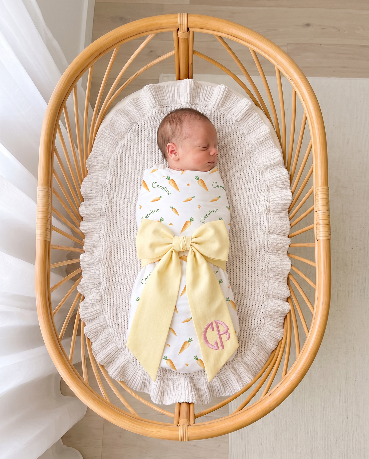 Personalized Newborn Bow Sash in Light Yellow on a swaddled newborn in a rattan bassinet