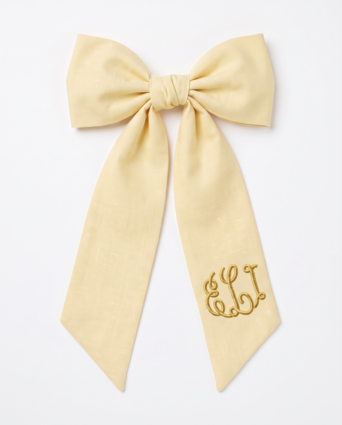 Light yellow linen-cotton bow sash tied in a bow with embroidered monogram