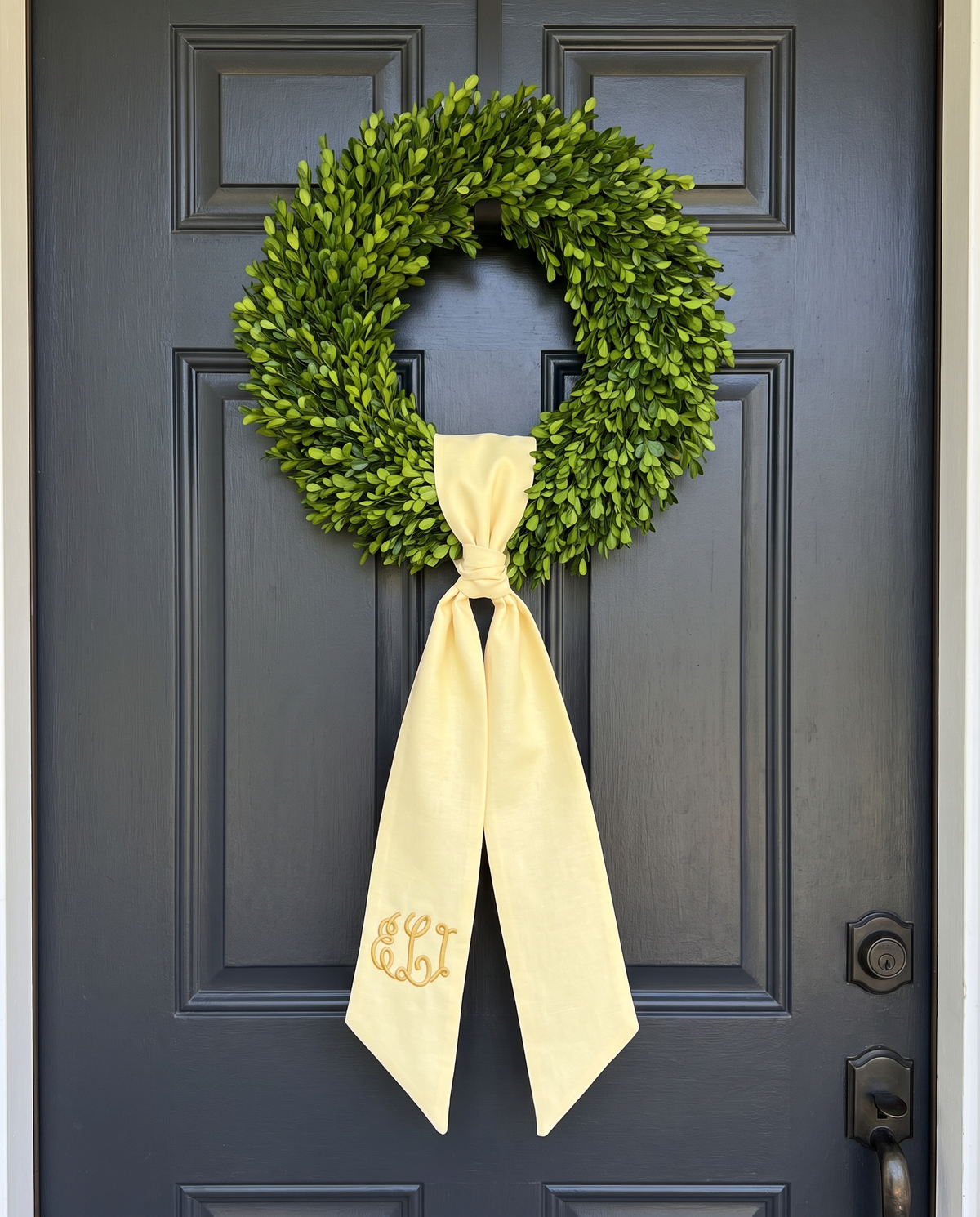 Light yellow bow sash hung on a front door wreath as a decorative accent