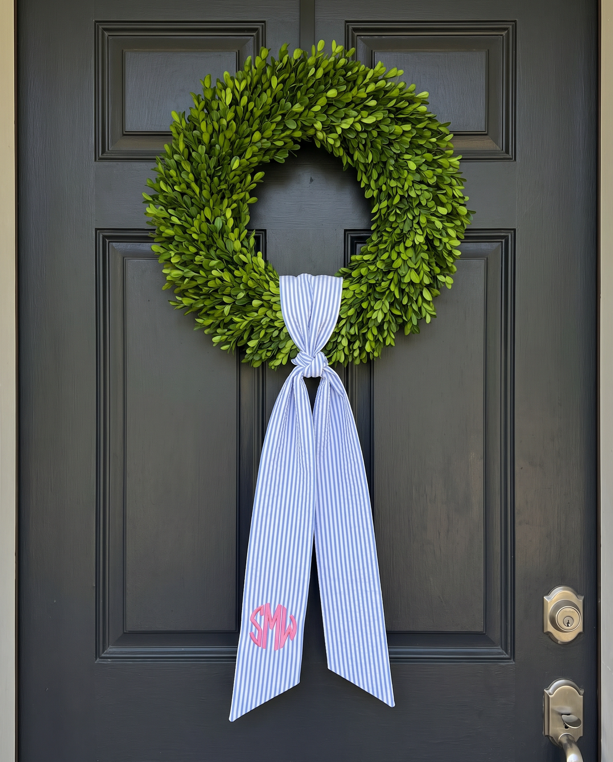 Striped blue bow sash hung on a front door wreath as a decorative accent