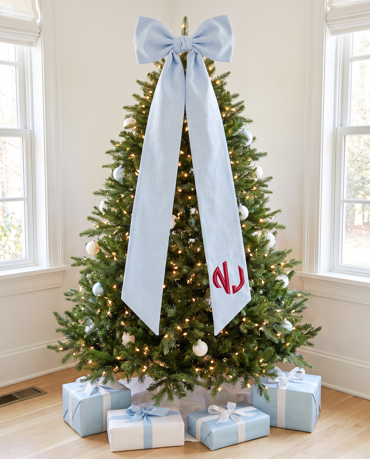 Light blue monogrammed bow sash used as a Christmas tree accent with blue and white gifts