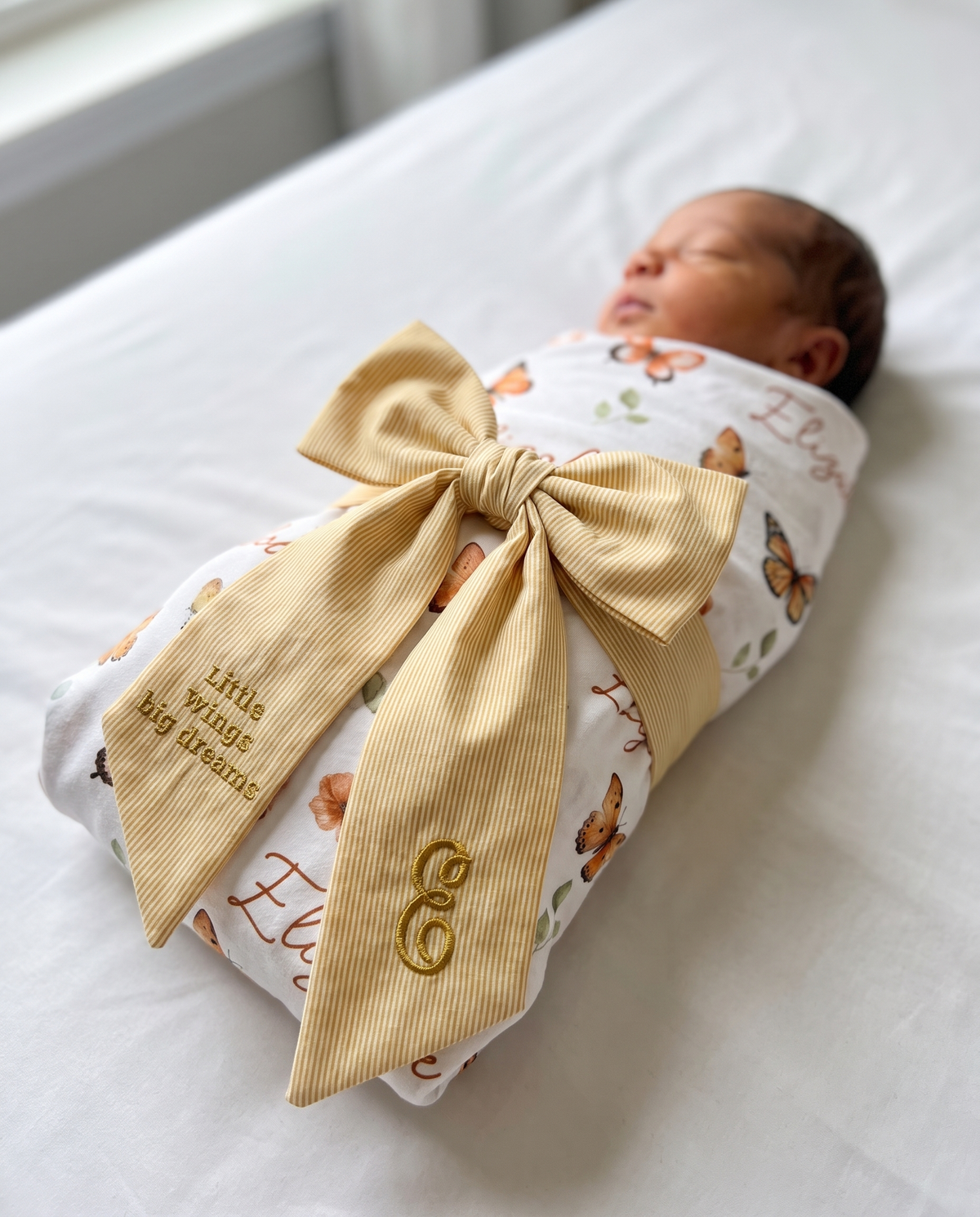 Newborn with striped yellow bow sash and Orange Butterfly swaddle