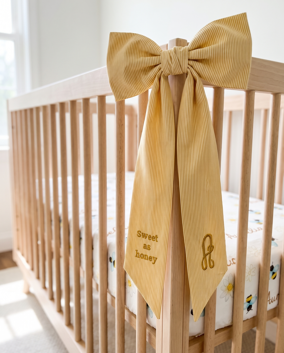 Striped yellow bow sash tied on a wooden crib corner