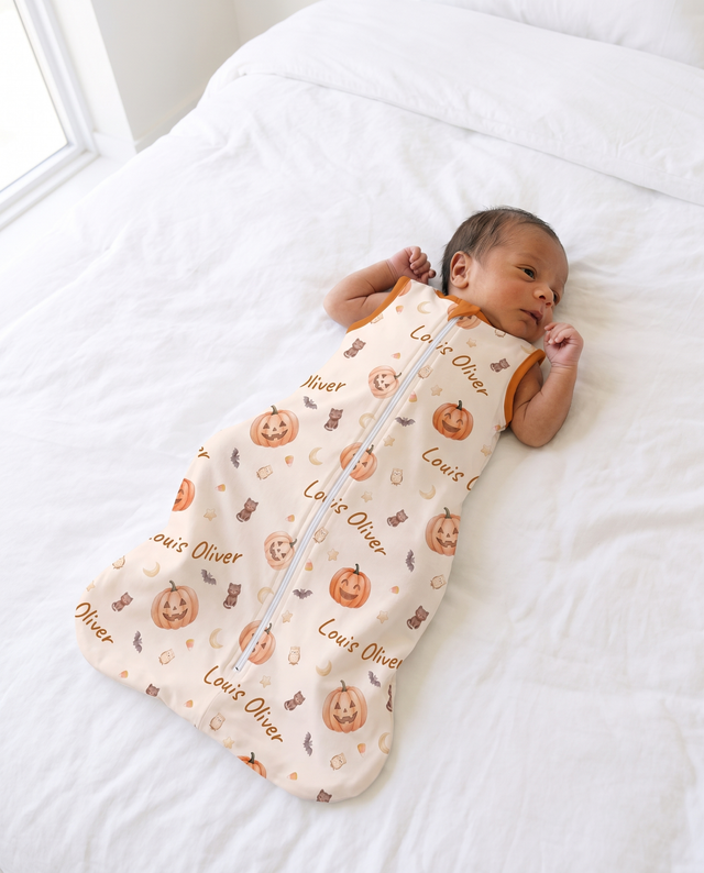 Awake baby twisting gently in the personalized sleep bag in Golden Jack pumpkin print