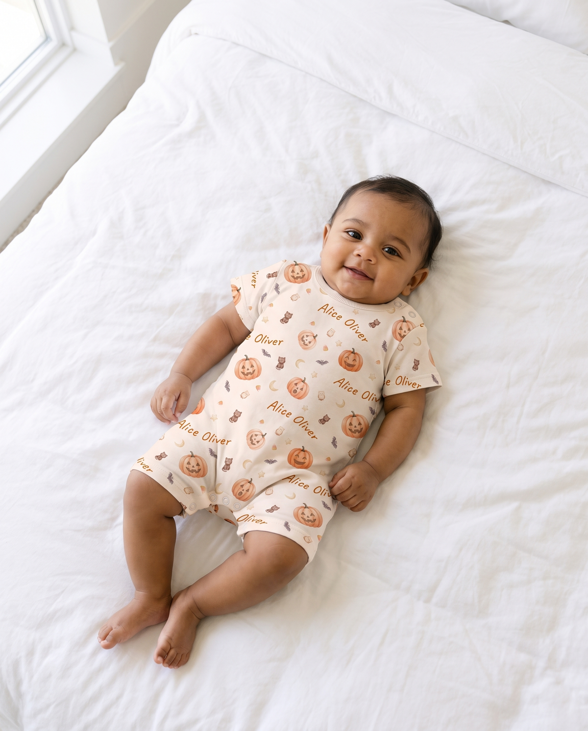Baby lying flat wearing personalized short-sleeve snap romper in Golden Jack pumpkin print
