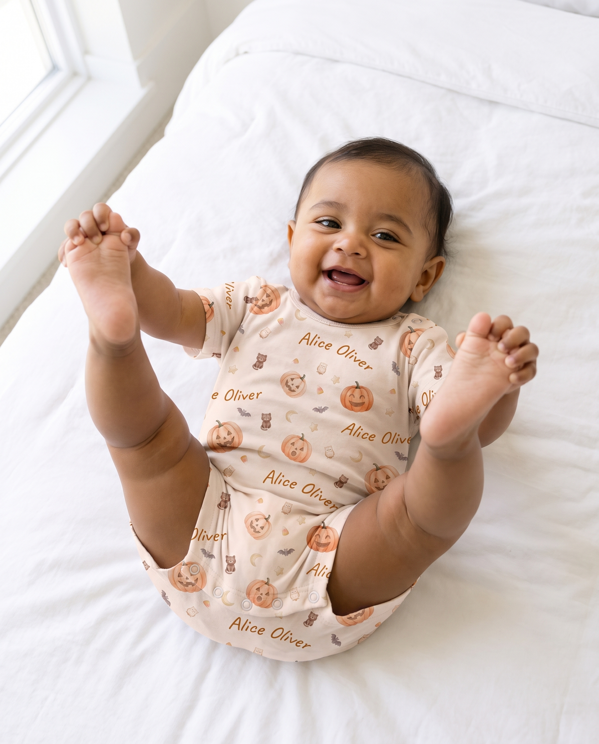 Smiling baby holding feet in the Golden Jack short-sleeve snap romper