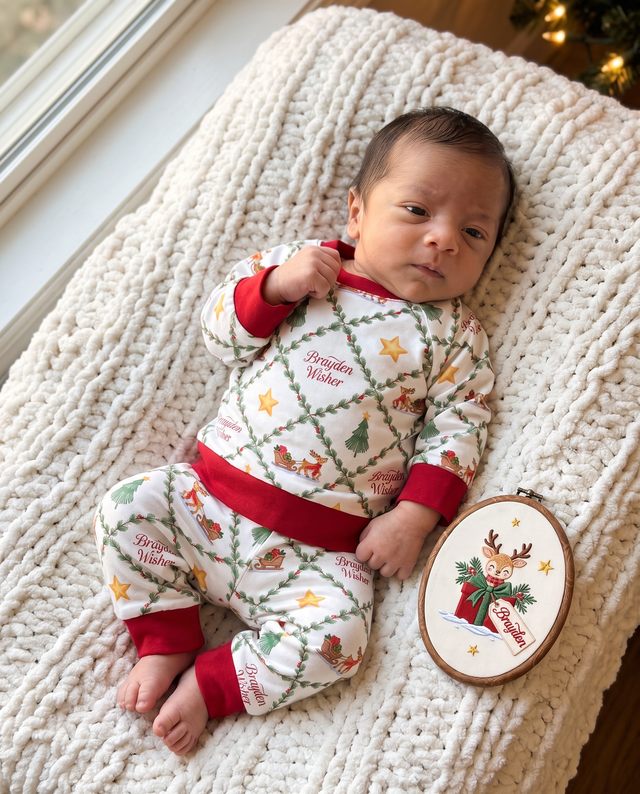 Baby in North Trail pajamas next to an embroidered name sign