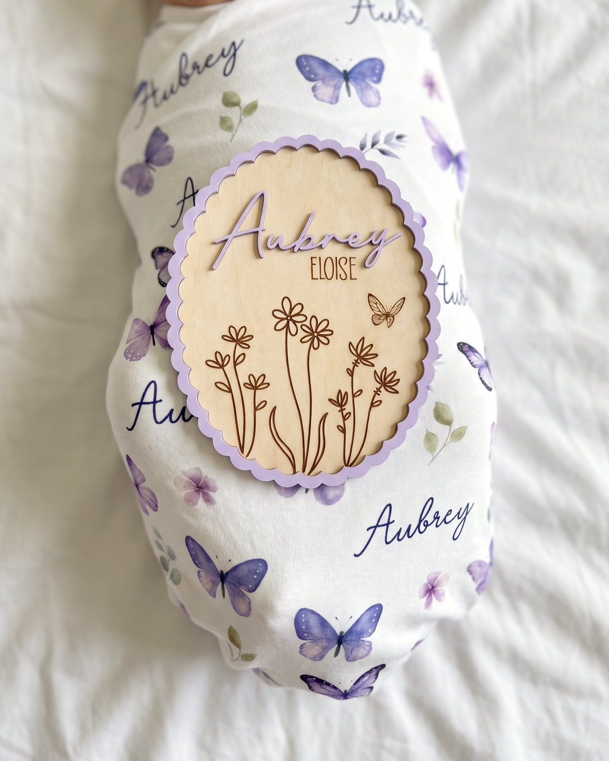 Scalloped Bloom wood birth announcement sign resting beside a newborn baby