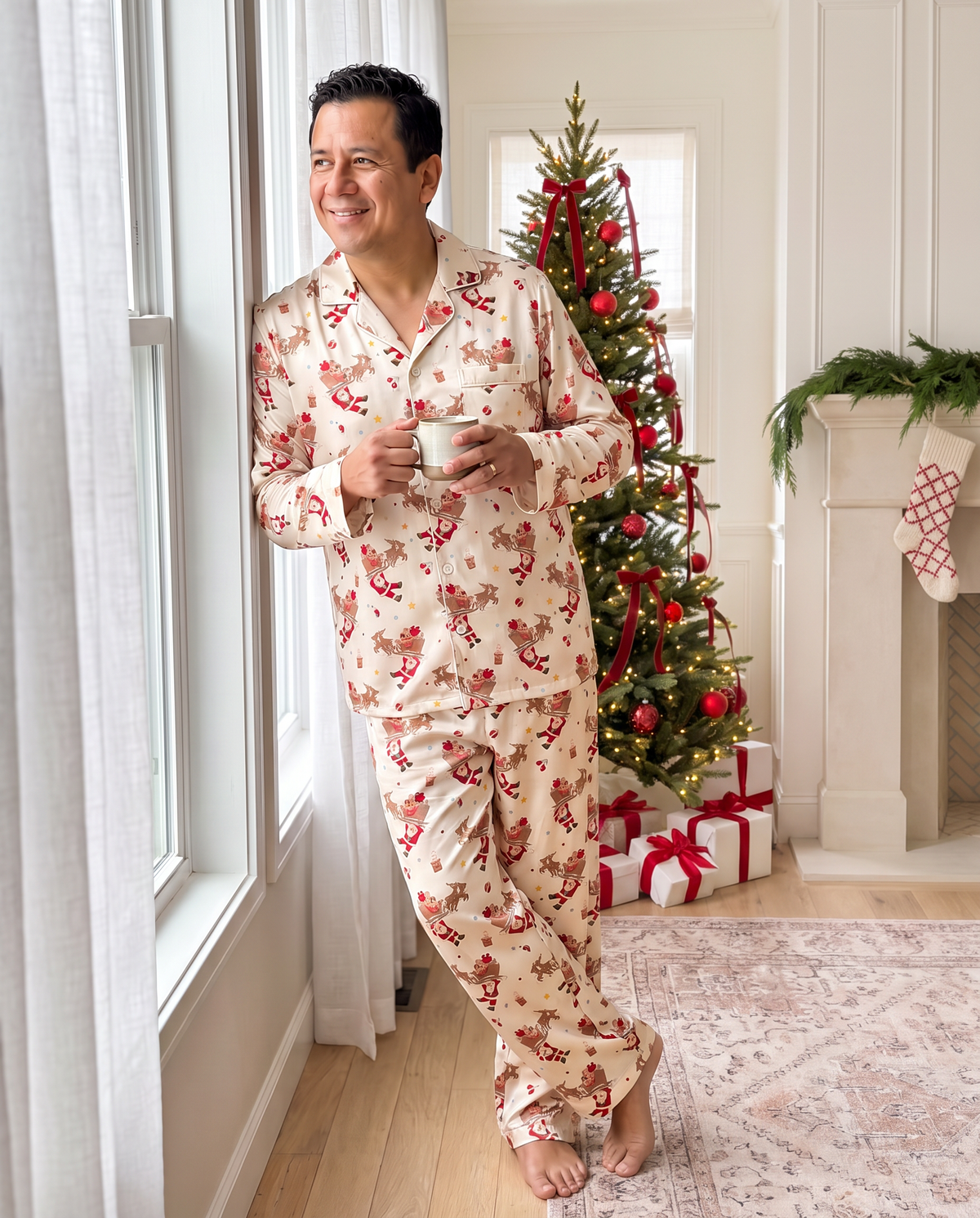 Man in Santa's Joyride pajamas with coffee by the window and Christmas tree