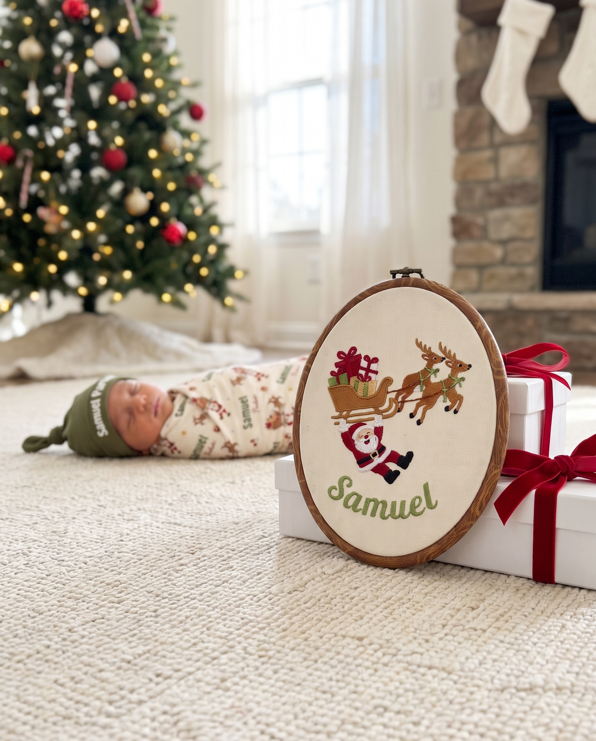 Personalized embroidered hoop sign leaning on Christmas gifts with a sleeping baby behind
