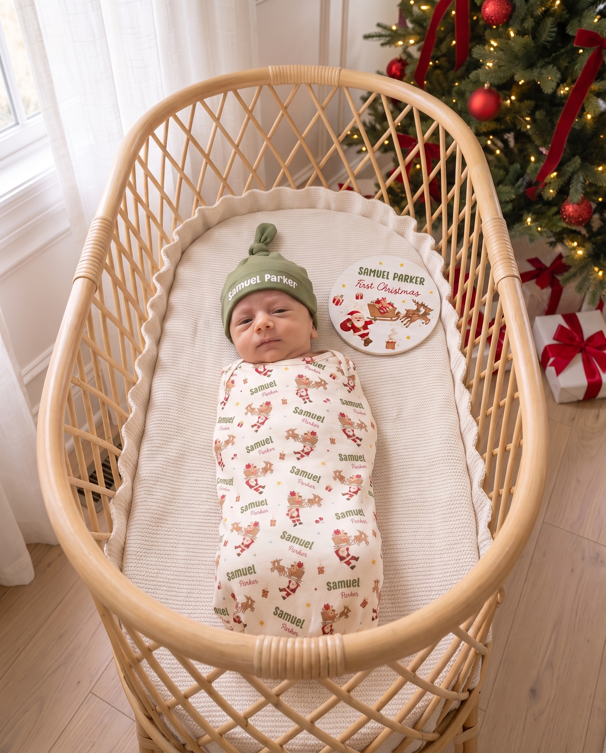 Swaddled baby with the personalized name sign in a rattan bassinet by the Christmas tree