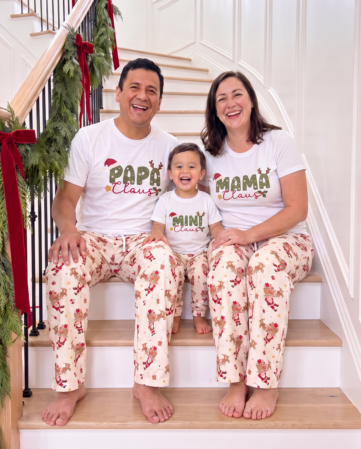 Family in matching Santa's Joyride lounge pants and Claus tees on the staircase