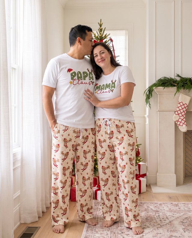Couple in Santa's Joyride lounge pants and Papa and Mama Claus tees by the window
