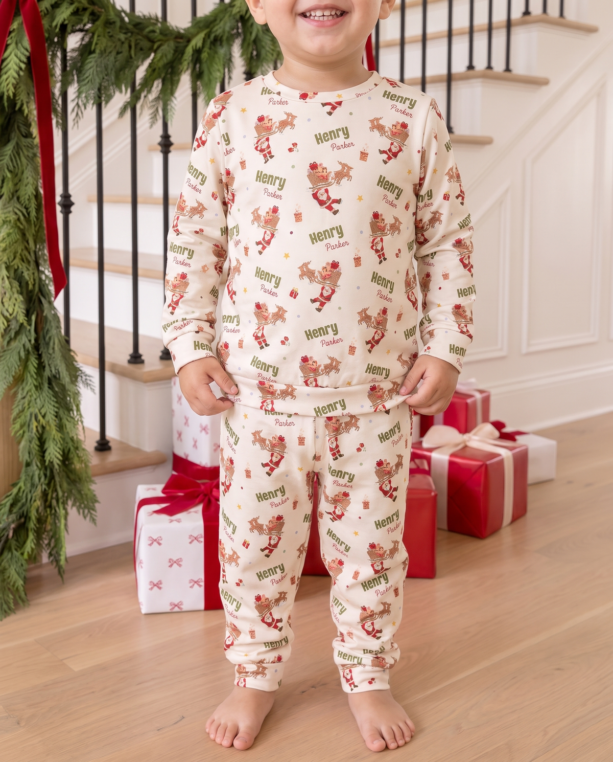 Toddler in the Santa's Joyride two piece pajamas standing by gifts and garland