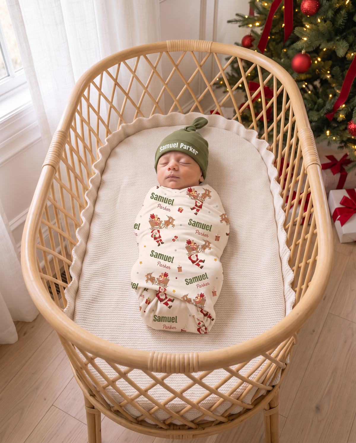 Baby wrapped in the Santa's Joyride swaddle and olive knotted hat sleeping in a rattan bassinet