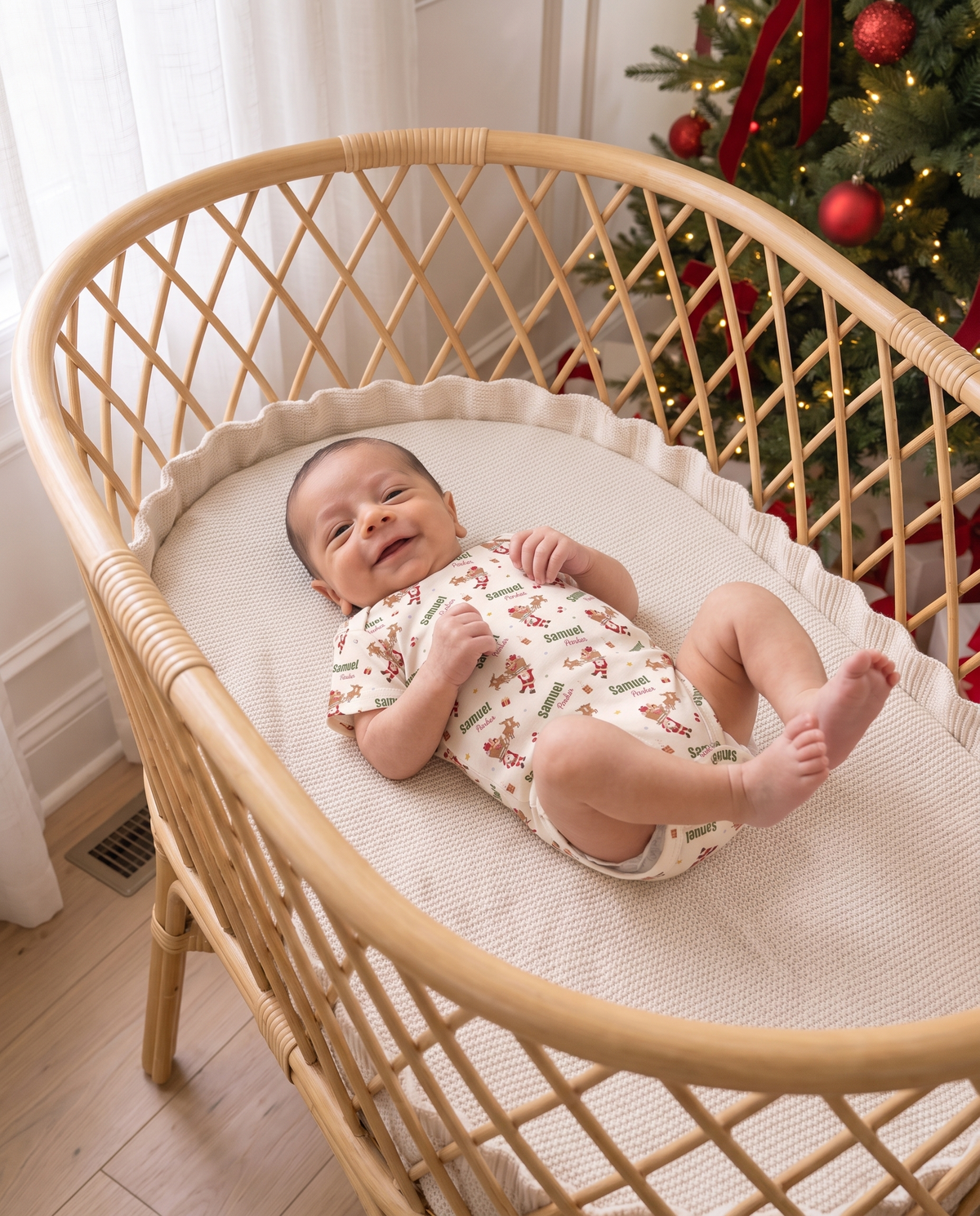 Baby in the Santa's Joyride bodysuit lying in a rattan bassinet near the Christmas tree