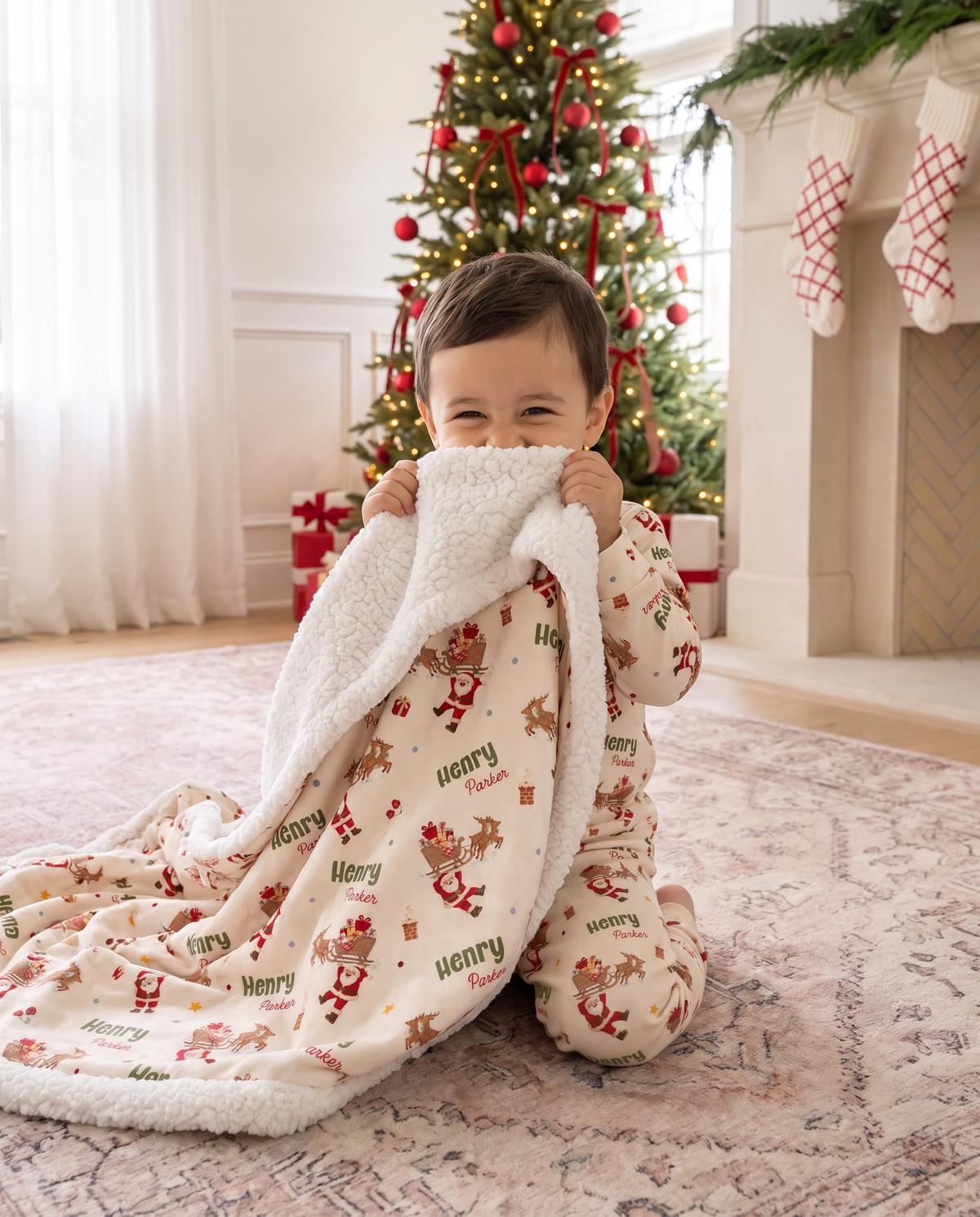 Toddler snuggled in the Santa's Joyride sherpa blanket on the rug by the Christmas tree